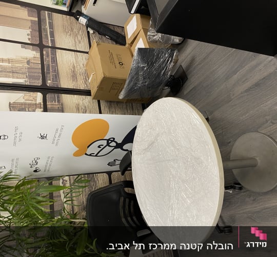 שולחן עגול עטוף בניילון, קרטונים וציוד משרדי